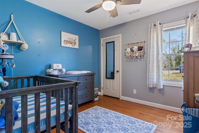 bedroom with multiple windows, wood finished floors, visible vents, and baseboards