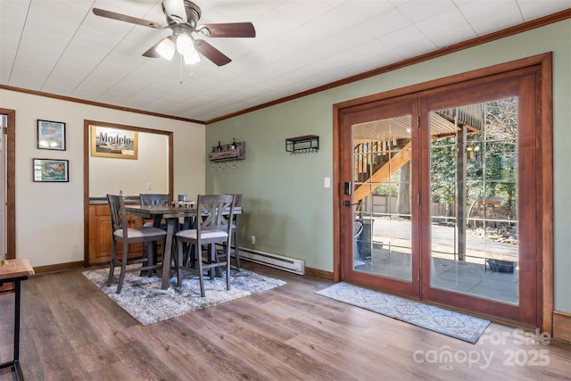 dining room with wood finished floors, crown molding, baseboards, and a baseboard radiator