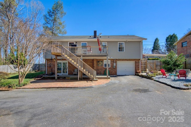 back of property featuring stairway, a garage, fence, and brick siding