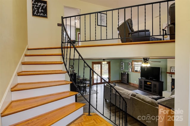 staircase with baseboards, a high ceiling, and ceiling fan