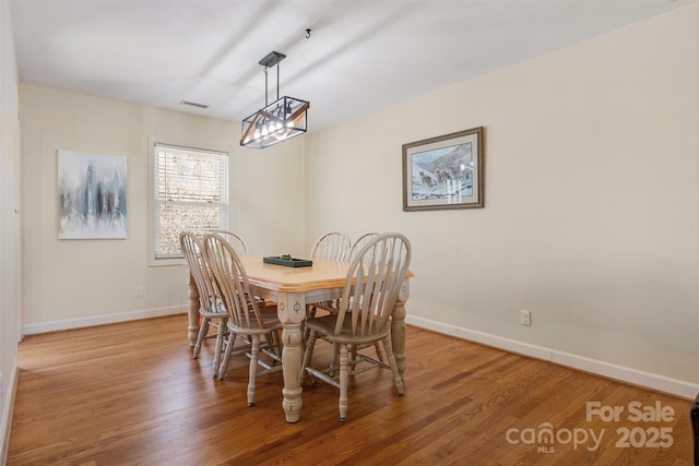 dining area featuring visible vents, baseboards, light wood-style floors, and an inviting chandelier