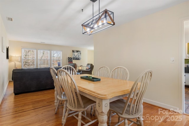 dining room featuring visible vents, light wood-style floors, and baseboards