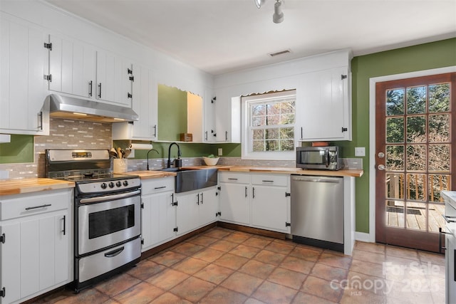 kitchen with visible vents, butcher block countertops, under cabinet range hood, a sink, and appliances with stainless steel finishes
