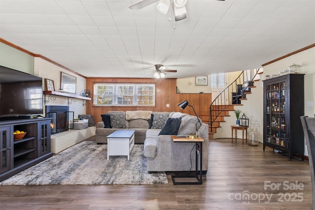 living room featuring a fireplace, stairway, wood finished floors, and ceiling fan
