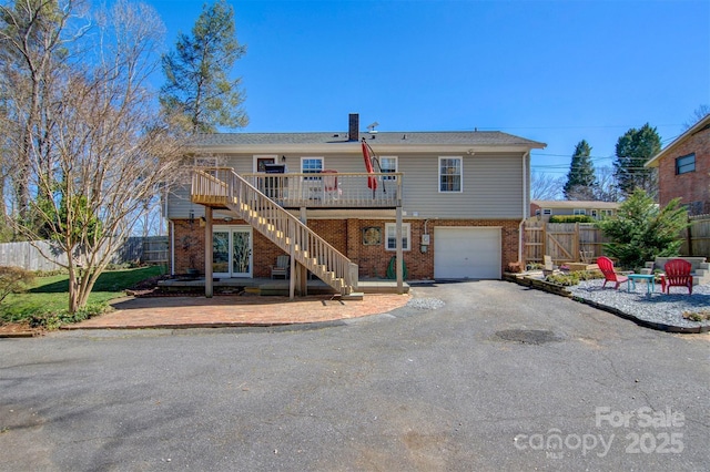 back of property with brick siding, stairway, a garage, and fence
