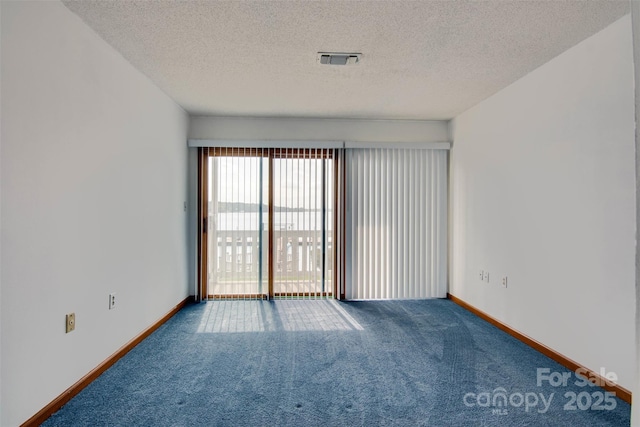 empty room with carpet, a textured ceiling, and visible vents