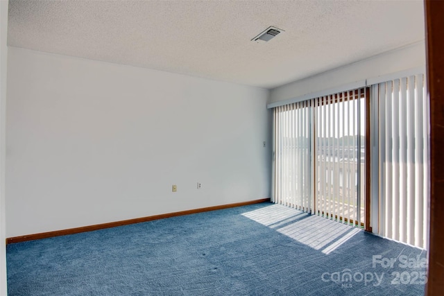 carpeted spare room with baseboards, visible vents, and a textured ceiling