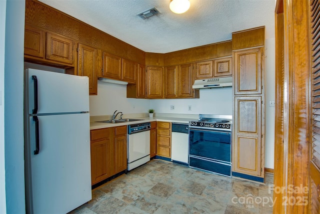 kitchen with a sink, white appliances, visible vents, under cabinet range hood, and light countertops