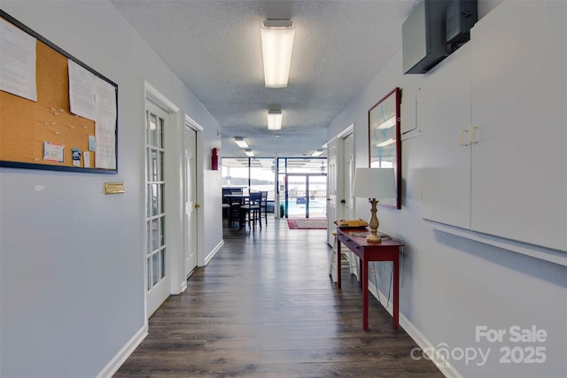hall featuring baseboards, dark wood-style flooring, and a textured ceiling