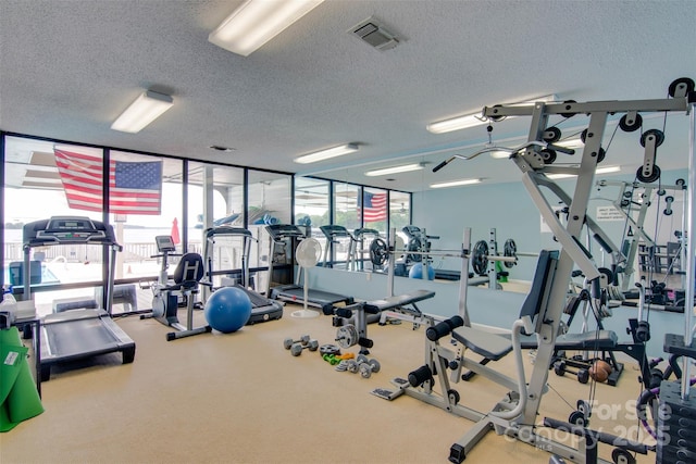 gym featuring a wall of windows, visible vents, and a textured ceiling