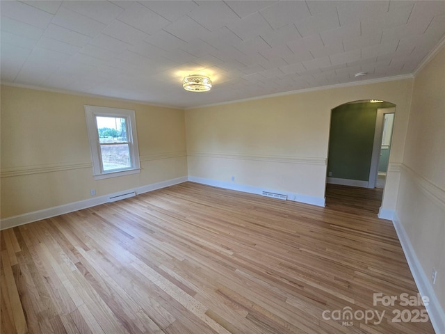 spare room with visible vents, crown molding, wood finished floors, and arched walkways