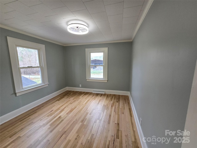 spare room with light wood finished floors, visible vents, crown molding, and baseboards