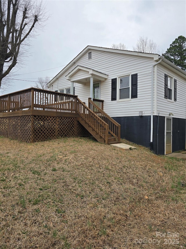 rear view of property featuring a yard and a deck