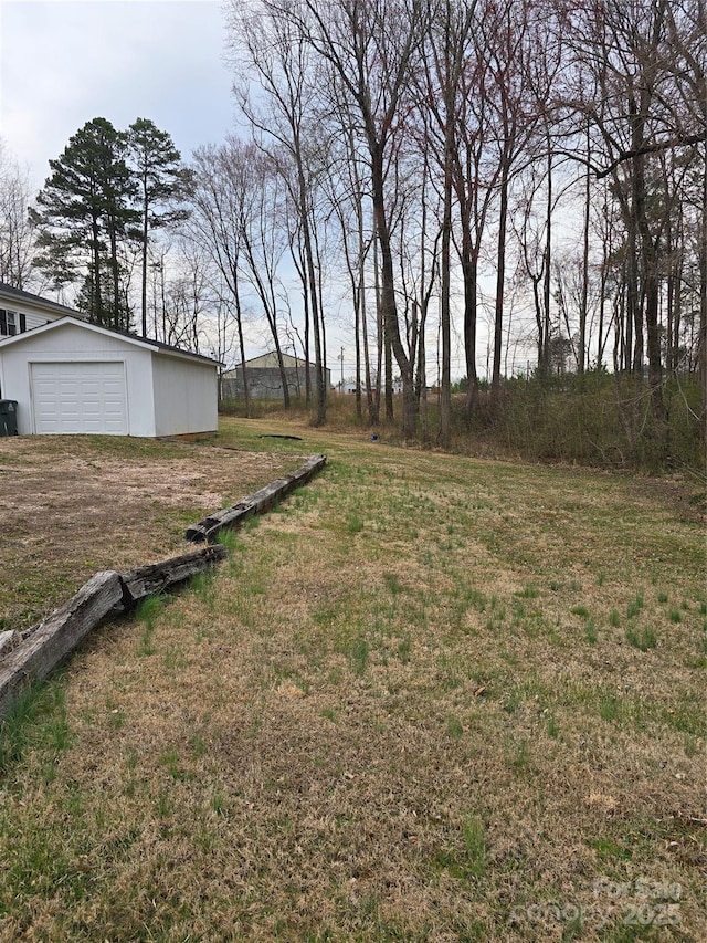 view of yard with an outbuilding, a garage, and dirt driveway