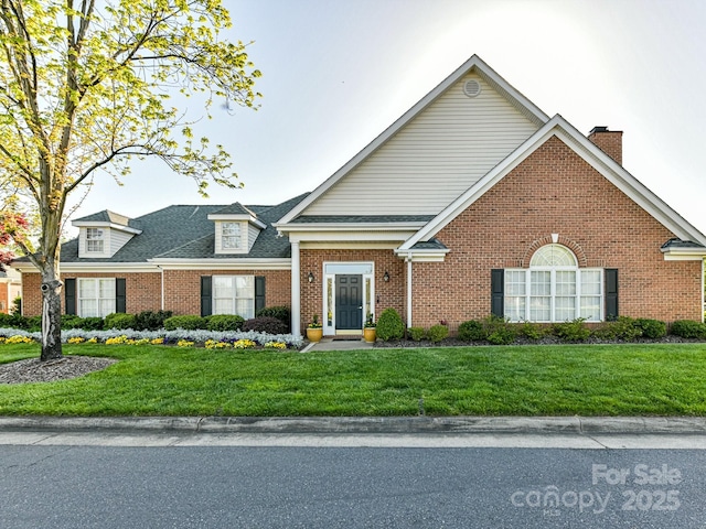 view of front of house with a front lawn, brick siding, and roof with shingles