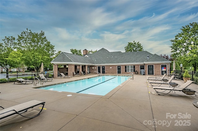 community pool with a patio and fence