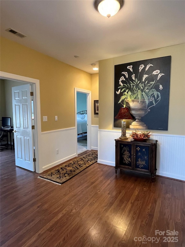 hall featuring visible vents, wood finished floors, and wainscoting