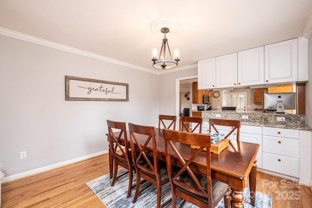 dining area featuring a notable chandelier, light wood-style flooring, baseboards, and ornamental molding