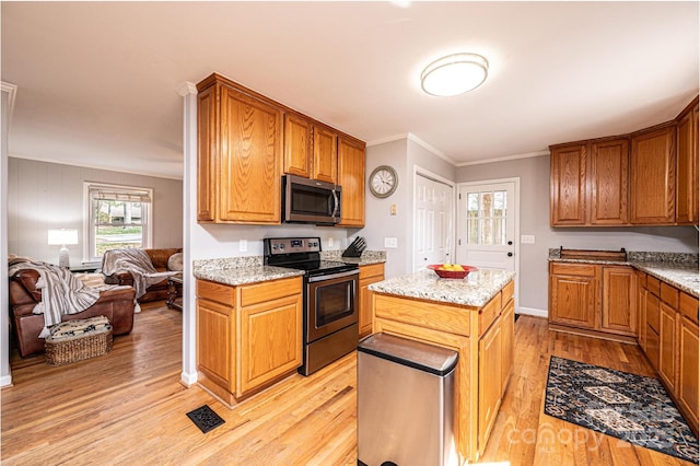 kitchen featuring light stone counters, light wood-style flooring, ornamental molding, stainless steel appliances, and open floor plan