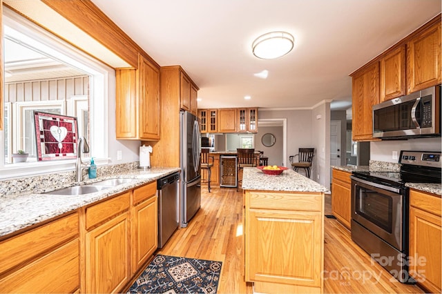 kitchen with light wood-style flooring, appliances with stainless steel finishes, a center island, and a sink