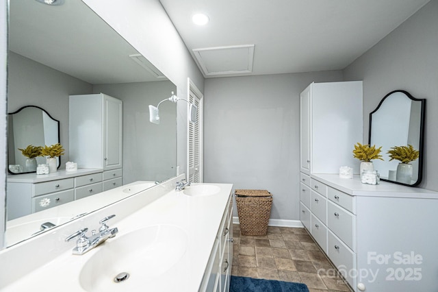 full bathroom featuring double vanity, baseboards, and a sink