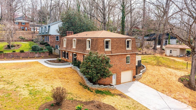 exterior space with brick siding, driveway, an attached garage, and a front yard