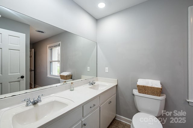 bathroom featuring a sink, visible vents, toilet, and double vanity