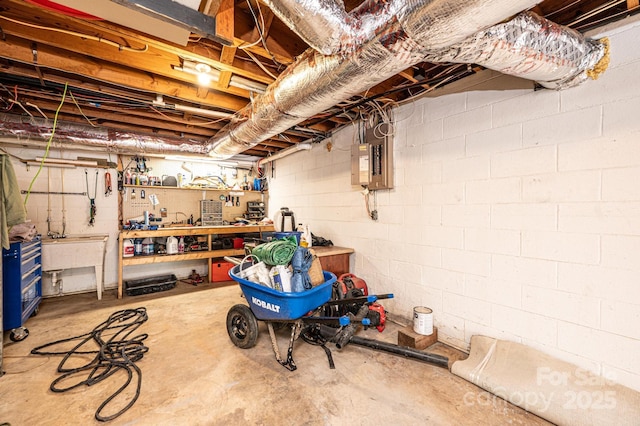 unfinished basement featuring a sink, a workshop area, and electric panel