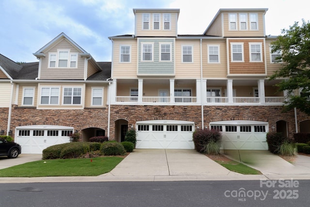 townhome / multi-family property with stone siding, driveway, and an attached garage