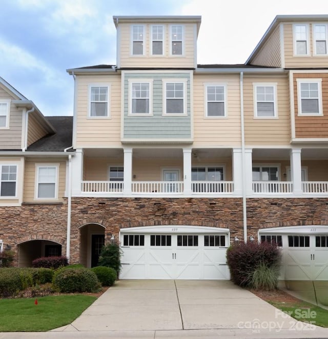 townhome / multi-family property featuring an attached garage, stone siding, and driveway