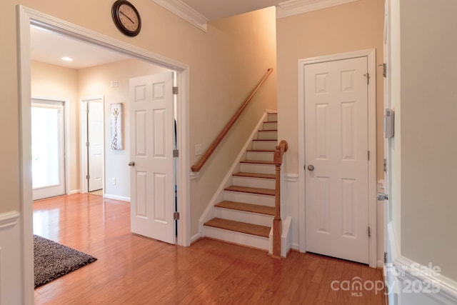 staircase with crown molding, wood finished floors, and baseboards