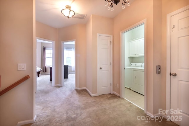 corridor featuring visible vents, baseboards, washer and clothes dryer, light colored carpet, and a chandelier
