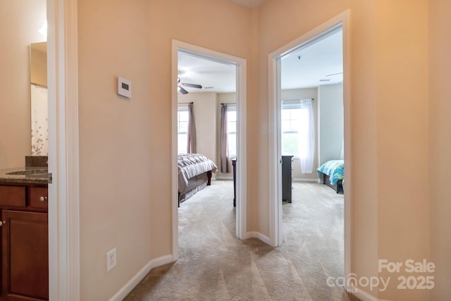 corridor with light colored carpet and baseboards
