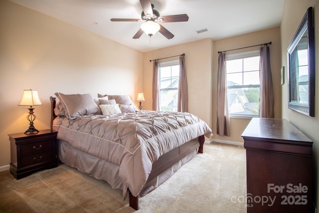 bedroom featuring visible vents, light carpet, baseboards, and ceiling fan