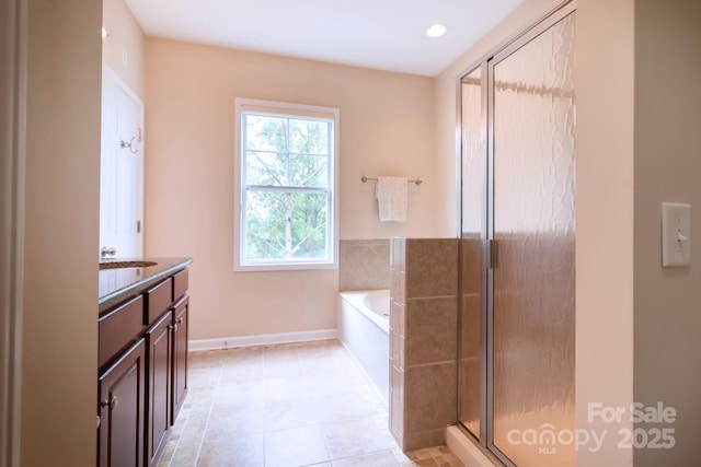 full bathroom with a stall shower, tile patterned flooring, baseboards, a bath, and vanity