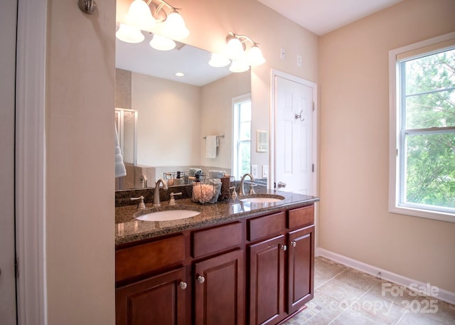 full bath featuring double vanity, tile patterned floors, baseboards, and a sink