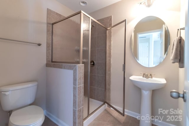 full bathroom featuring tile patterned flooring, a stall shower, toilet, and a sink