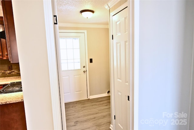 hall featuring a textured ceiling, crown molding, and light wood-style floors