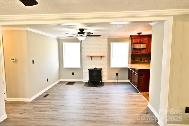 unfurnished living room with ornamental molding, a ceiling fan, a textured ceiling, wood finished floors, and a wood stove