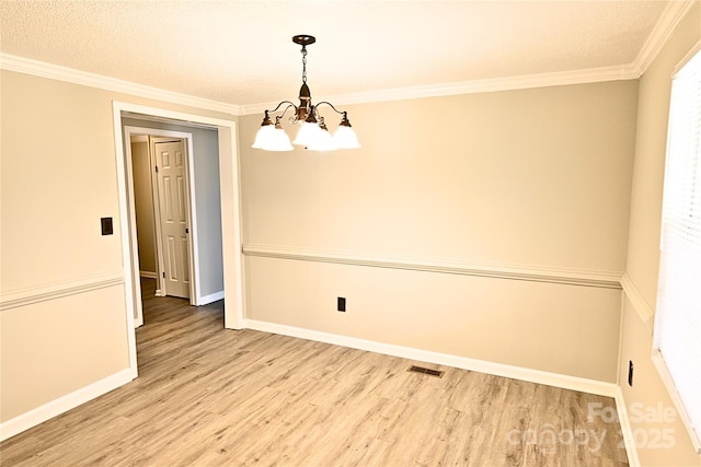 spare room with crown molding, a notable chandelier, and light wood-type flooring