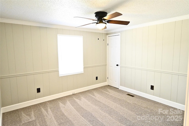 empty room featuring visible vents, carpet floors, ceiling fan, and ornamental molding