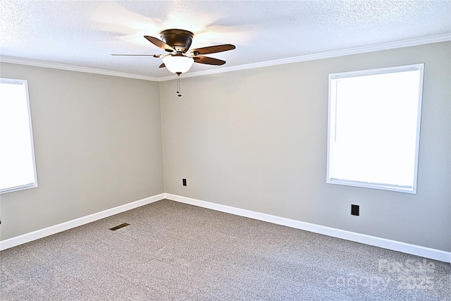 carpeted spare room featuring a wealth of natural light, visible vents, ceiling fan, and ornamental molding