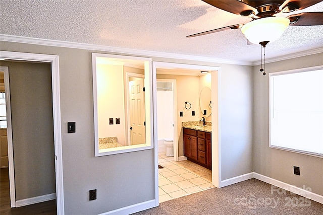 interior space featuring a ceiling fan, a sink, a textured ceiling, crown molding, and light colored carpet