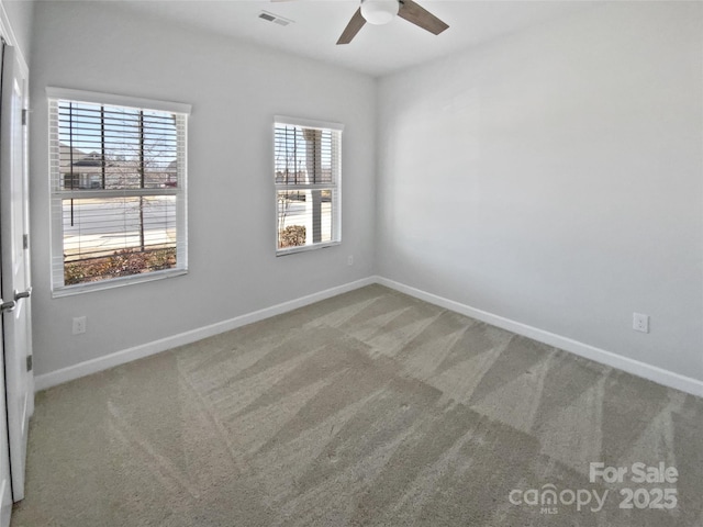 carpeted spare room featuring a wealth of natural light, visible vents, and baseboards