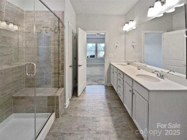 bathroom with a sink, baseboards, a stall shower, and double vanity