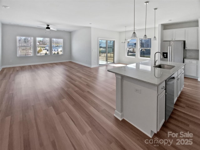 kitchen featuring light wood finished floors, open floor plan, appliances with stainless steel finishes, and a sink