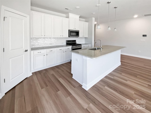 kitchen with backsplash, light wood-type flooring, appliances with stainless steel finishes, and a sink