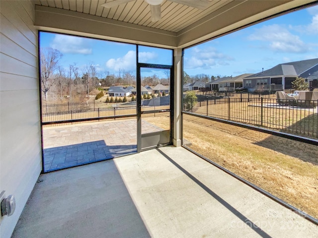 unfurnished sunroom featuring a residential view and ceiling fan