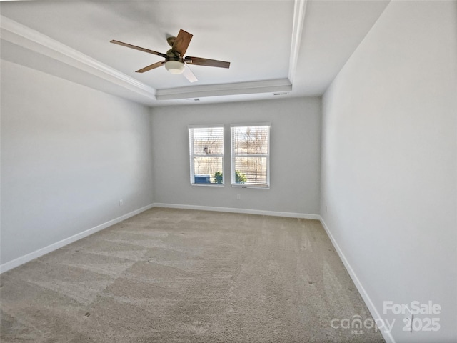 carpeted empty room with baseboards, a raised ceiling, a ceiling fan, and crown molding