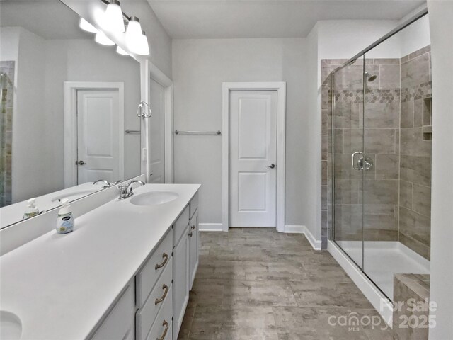 bathroom with vanity, baseboards, and a stall shower